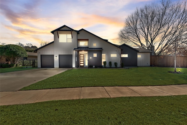 modern home featuring driveway, metal roof, a standing seam roof, fence, and a yard