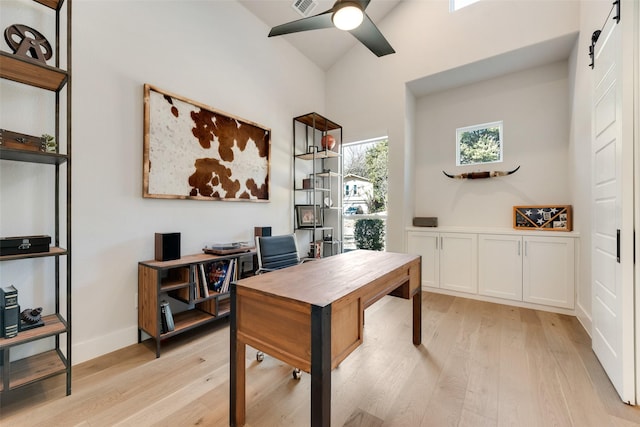 office featuring a barn door, visible vents, baseboards, a ceiling fan, and light wood-type flooring