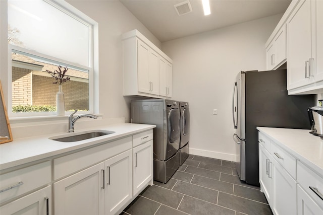 washroom featuring cabinet space, visible vents, a sink, independent washer and dryer, and dark tile patterned floors