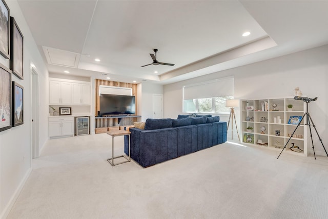 living room featuring a tray ceiling, light colored carpet, recessed lighting, and wine cooler