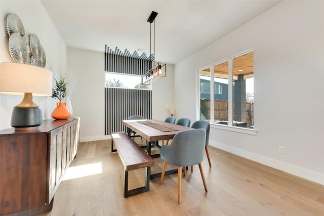 dining area featuring a notable chandelier, light wood-style flooring, and baseboards