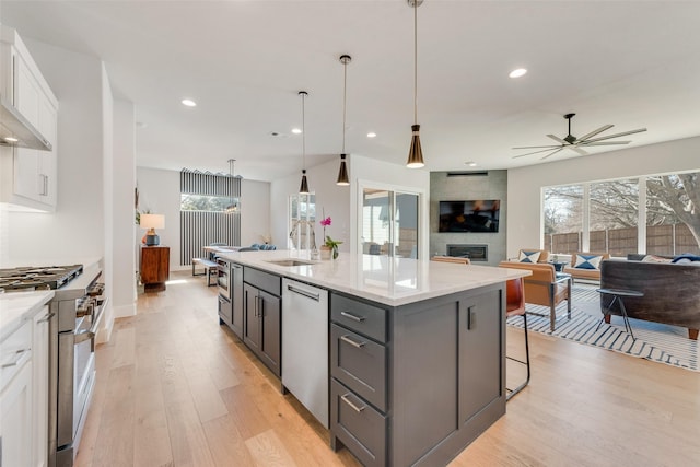 kitchen with white cabinets, light stone counters, open floor plan, a kitchen island with sink, and stainless steel appliances