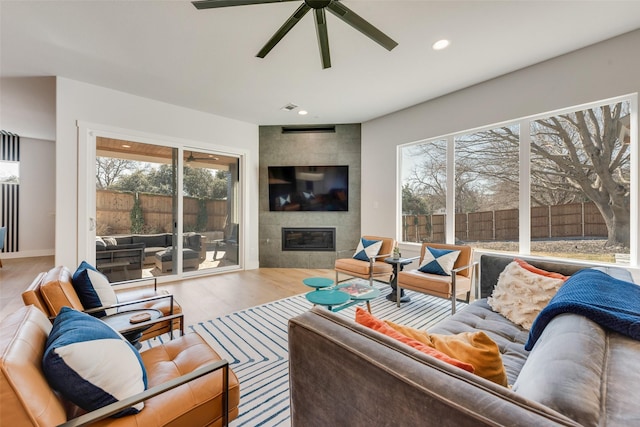 living area featuring recessed lighting, wood finished floors, visible vents, a ceiling fan, and a tiled fireplace