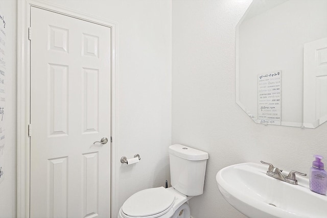 half bathroom featuring toilet and a sink