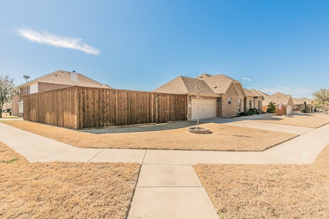 view of front of property with a garage, a residential view, brick siding, and driveway