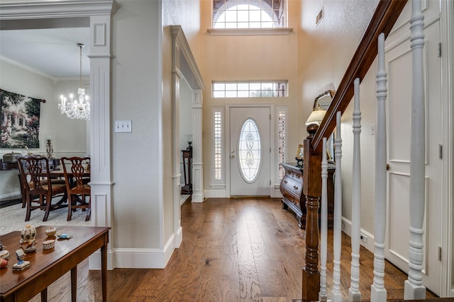 entrance foyer featuring a notable chandelier, baseboards, stairs, ornamental molding, and dark wood-style floors