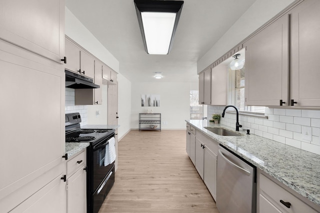 kitchen featuring light wood-style flooring, black / electric stove, stainless steel dishwasher, under cabinet range hood, and a sink