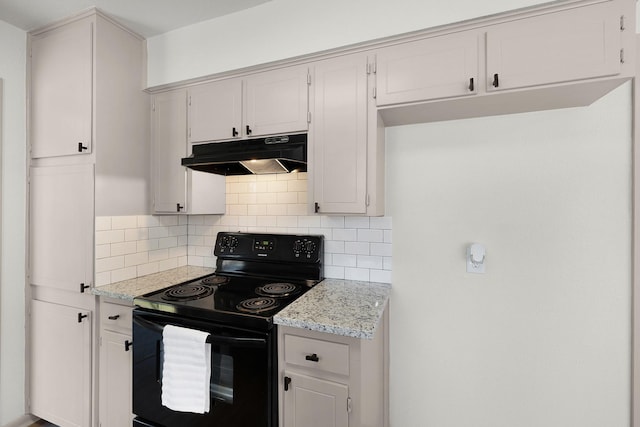 kitchen with light stone countertops, under cabinet range hood, black range with electric cooktop, and tasteful backsplash