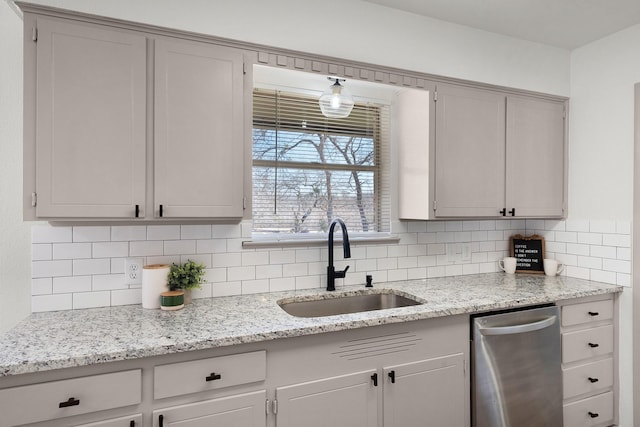 kitchen with dishwasher, light stone counters, backsplash, and a sink