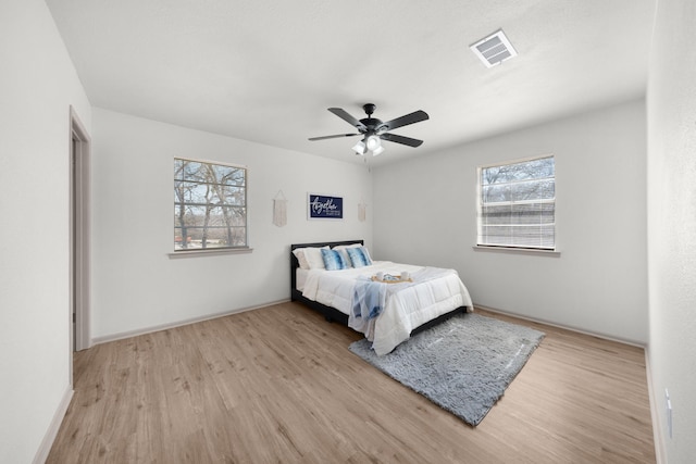 bedroom featuring ceiling fan, baseboards, visible vents, and light wood-style floors