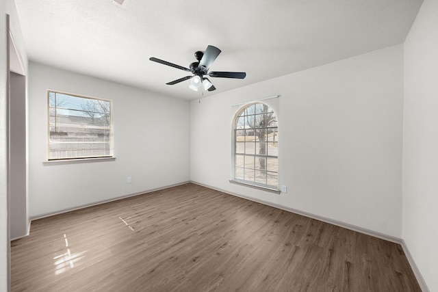 spare room with baseboards, a ceiling fan, and wood finished floors