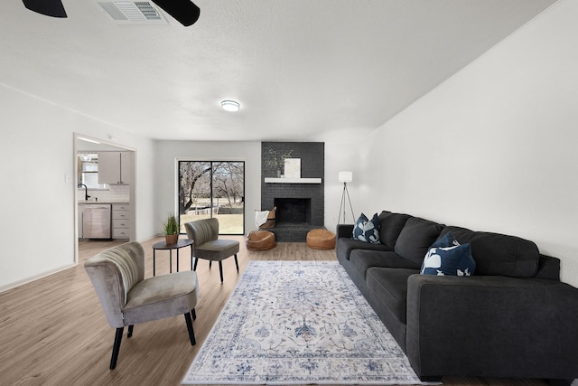 living area with visible vents, a fireplace, and light wood finished floors