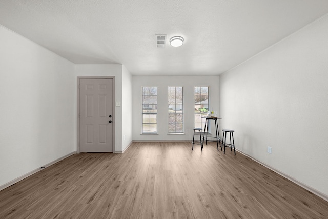 foyer featuring visible vents, a textured ceiling, light wood-style flooring, and baseboards