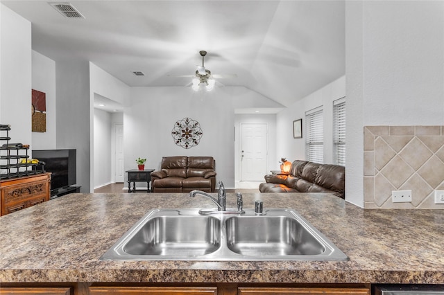 kitchen with dark countertops, open floor plan, visible vents, and a sink