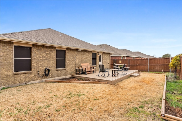 rear view of property with a fenced backyard, a lawn, a shingled roof, and brick siding