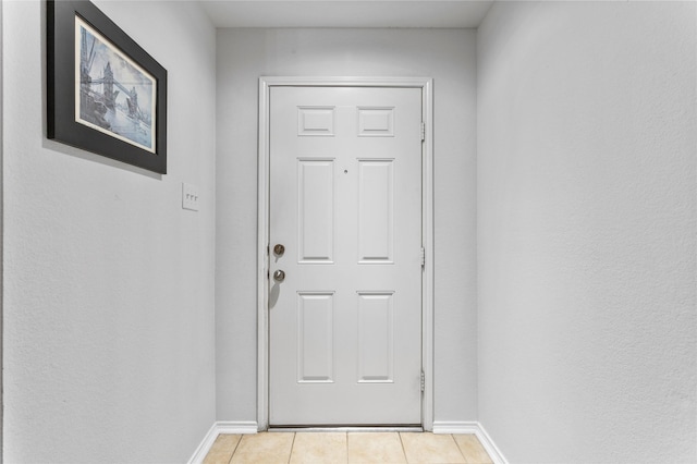 doorway featuring light tile patterned floors and baseboards