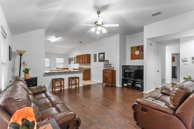 living area featuring visible vents, baseboards, dark wood-style floors, ceiling fan, and vaulted ceiling