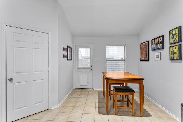 dining room with lofted ceiling, baseboards, and light tile patterned floors