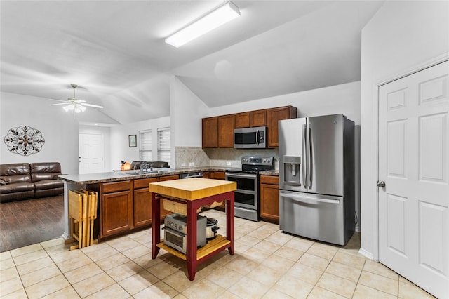 kitchen with lofted ceiling, appliances with stainless steel finishes, open floor plan, a sink, and a peninsula