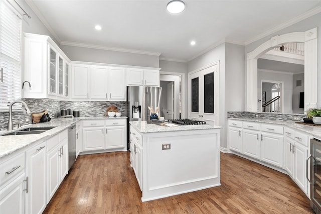 kitchen with light stone countertops, white cabinetry, stainless steel appliances, and a sink