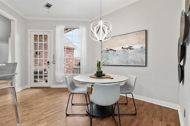 dining space with visible vents, baseboards, wood finished floors, crown molding, and a notable chandelier