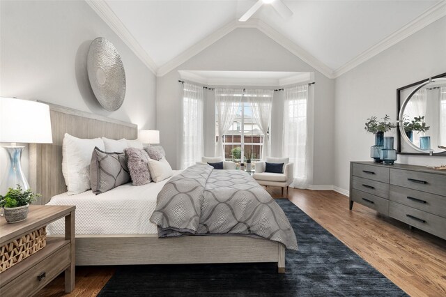 bedroom with lofted ceiling, ornamental molding, wood finished floors, and baseboards