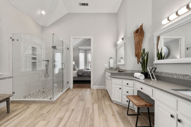 ensuite bathroom featuring vaulted ceiling, wood finished floors, connected bathroom, and visible vents