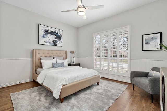 bedroom with a wainscoted wall, ceiling fan, and wood finished floors