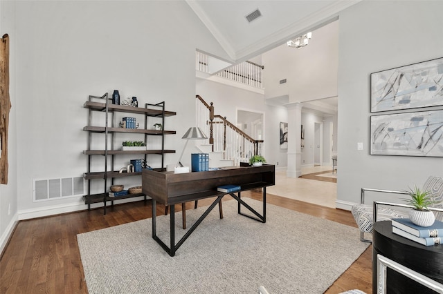 office featuring baseboards, visible vents, ornate columns, and wood finished floors