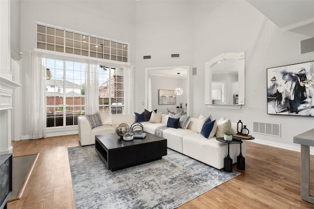 living room featuring a high ceiling, wood finished floors, and visible vents