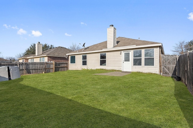 rear view of property featuring a lawn, a chimney, and a fenced backyard