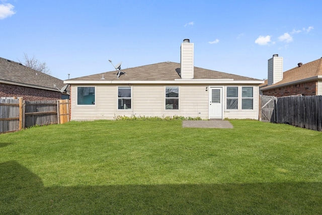 back of property featuring a fenced backyard, a lawn, and a chimney