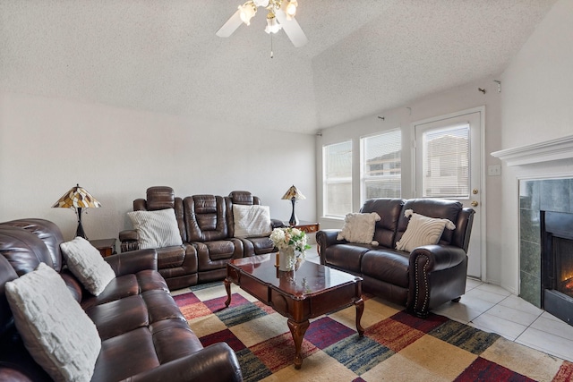 living room with a tile fireplace, ceiling fan, a textured ceiling, and light tile patterned floors