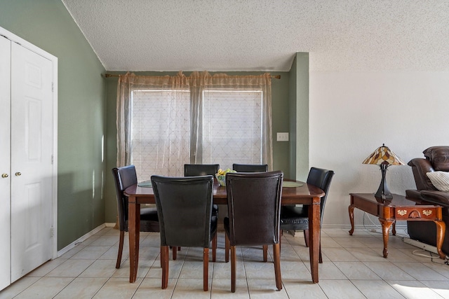 dining space featuring a textured ceiling, baseboards, and light tile patterned floors