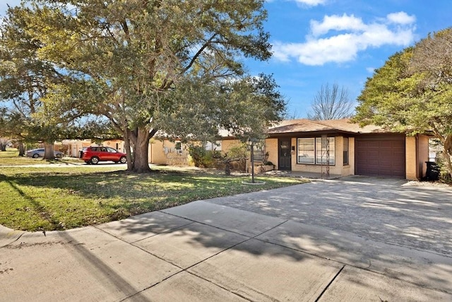 ranch-style house featuring driveway, brick siding, an attached garage, and a front yard