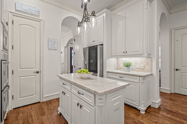 kitchen with arched walkways, a center island, hanging light fixtures, stainless steel appliances, and white cabinetry