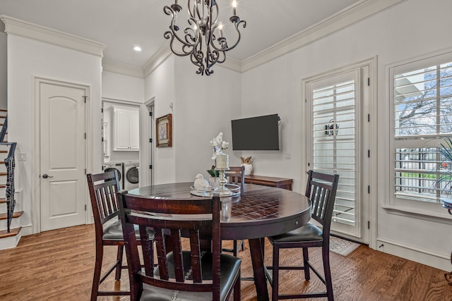 dining room with a chandelier, separate washer and dryer, wood finished floors, and ornamental molding