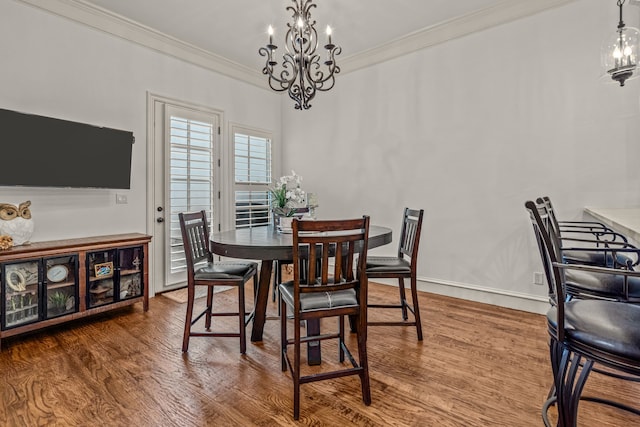 dining area featuring baseboards, ornamental molding, wood finished floors, and a notable chandelier