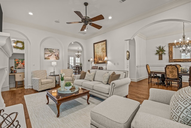 living area featuring crown molding, arched walkways, wood finished floors, and recessed lighting