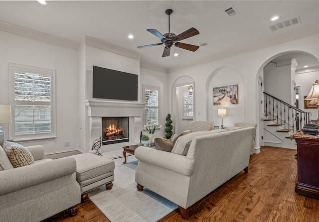 living area featuring visible vents, dark wood-type flooring, a lit fireplace, stairs, and recessed lighting