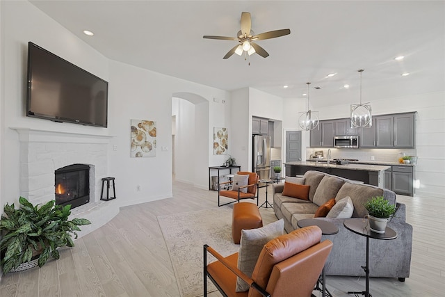 living area with light wood-style flooring, recessed lighting, a ceiling fan, and arched walkways