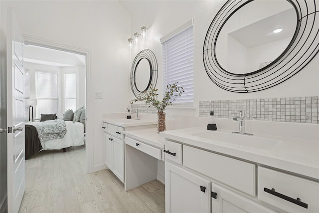 full bath featuring double vanity, ensuite bath, a sink, and wood finished floors