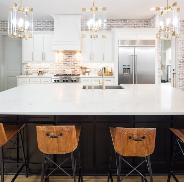 kitchen with premium range hood, a sink, stainless steel appliances, a large island, and a chandelier