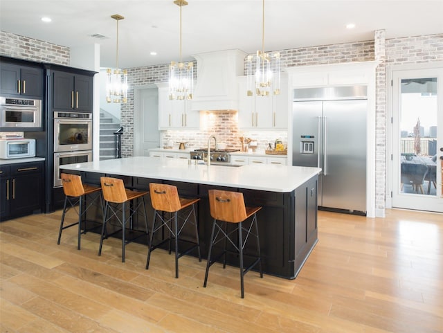 kitchen with brick wall, a breakfast bar, light countertops, custom exhaust hood, and stainless steel appliances