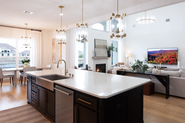 kitchen featuring visible vents, a lit fireplace, a sink, stainless steel dishwasher, and open floor plan