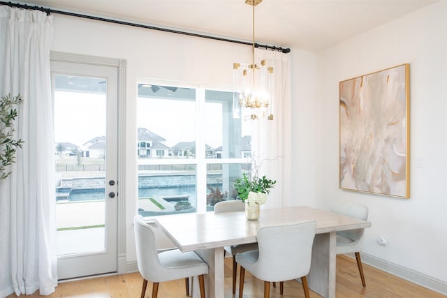 dining room with a chandelier, light wood finished floors, and baseboards