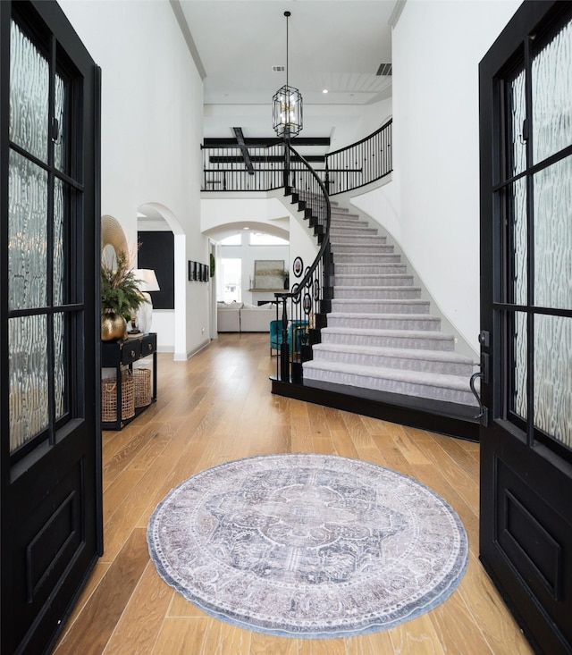 entryway featuring a chandelier, stairway, a high ceiling, wood finished floors, and arched walkways