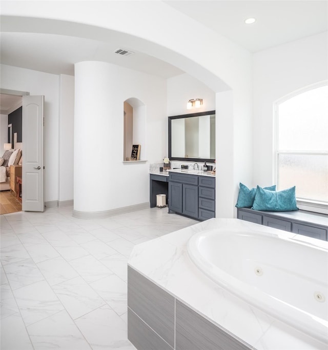 full bath featuring vanity, baseboards, visible vents, a jetted tub, and marble finish floor