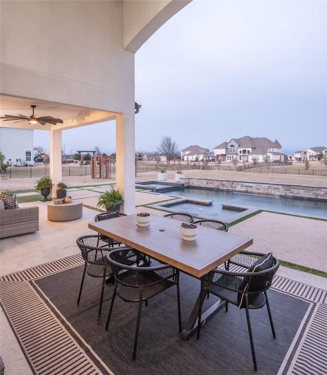 view of patio with a jacuzzi, fence, an outdoor pool, and a water view