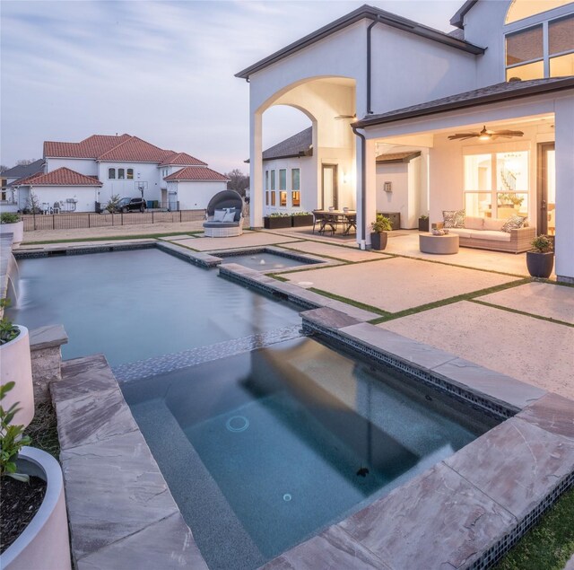 view of swimming pool featuring a patio area, fence, a pool with connected hot tub, and an outdoor hangout area